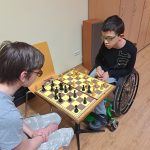 Rozgrywki szachowe. Dwóch chłopców siedzi naprzeciwko siebie przy stole i gra w szachy.