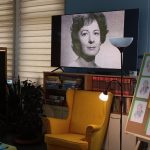 Młodzież ogląda zdjęcia młodej Wisławy Szymborskiej wyświetlane na ekranie telewizora w świetlicy.