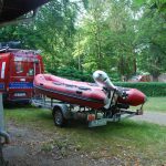 Sprzęt ratowniczy Wodnej Służby Ratowniczej. Czerwony samochód i ponton.